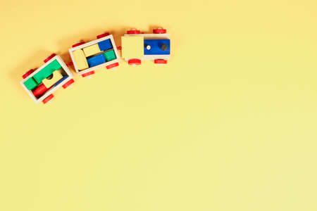 Baby kid toy background. Top view to wooden toy train with colorful blocks on yellow backgroundの写真素材