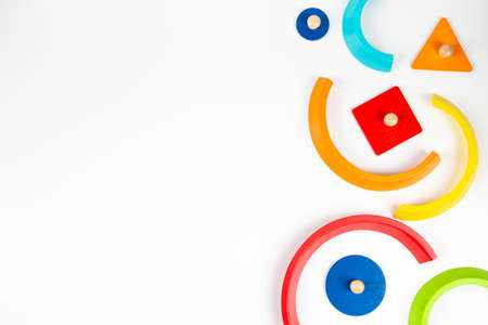 Wooden geometric shapes colorful toy figures composition on white background. Top view