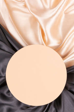 Circle platform podium on elegant black and champagne color background with drapery and wavy folds of silk satin clothの写真素材