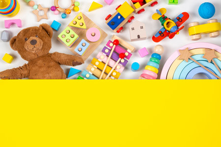 Top view to baby kids toys. Set of colorful educational wooden and fluffy toys and yellow blank background with copy space for textの写真素材