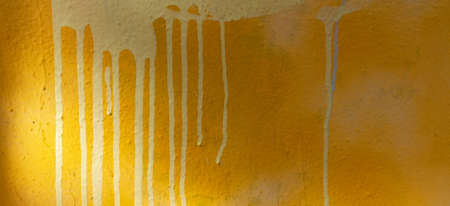 Yellow painted plastered wall background with colorful drips, flows, streaks of paint and paint...