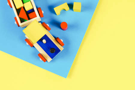 Baby kid toys background. Wooden toy train with colorful blocks on light blue and yellow background. Top viewの写真素材