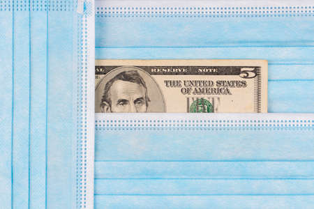 Disposable protective medical face masks and dollar banknote on blue background. Top view