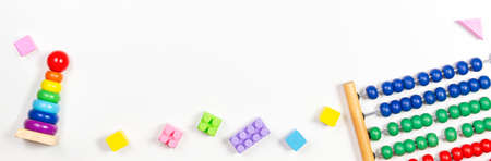 Baby kid toys banner background. Wooden baby stacking rings pyramid, abacus and colorful blocks on white table. Top viewの写真素材