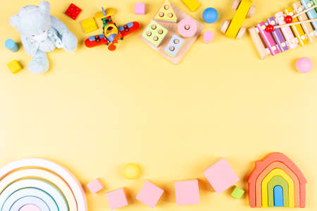 Baby kids toy frame with educational, developmental, musical, learning toys on pastel yellow background. Top view, flat lay, copy space in the middle.の写真素材