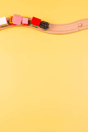 Toy train with curved wooden railways on yellow background. Top view