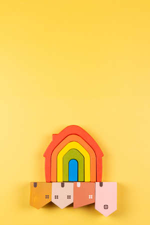 Rainbow flag toy house and small pastel color wooden houses below on yellow backgroundの写真素材
