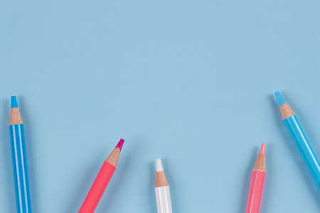 Colored pencils on light blue background. Pastel pink, blue, white colors. Top viewの写真素材