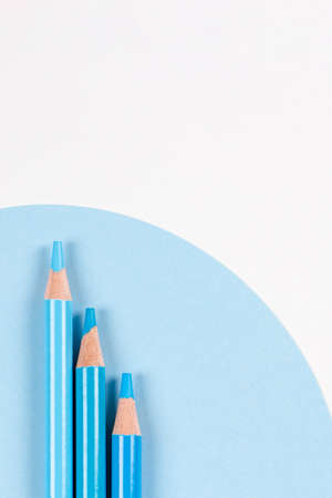 Light blue colored pencils on geometric blue and white background. Minimalistic geometric lines, monochrome colors. Top viewの写真素材