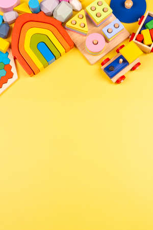 Baby kids toys frame. Educational wooden plastic and fluffy toys for children on yellow background. Top view, flat layの写真素材