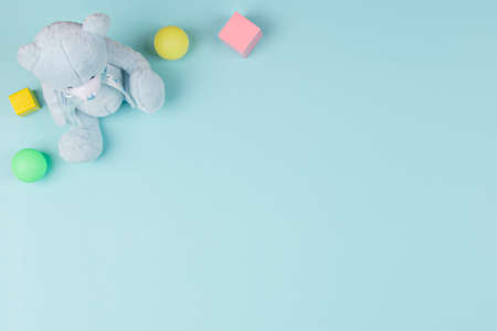 Baby kids toys background with teddy bear, wooden blocks and colorful balls on light blue color background. Top view, flat layの写真素材