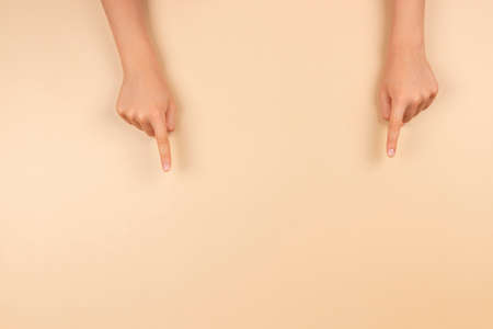 Hands pointing with index finger down to something on pastel backgroundの写真素材