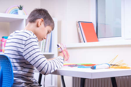 Teenage boy creating new 3d object with 3d pen. Learning and entertainment at homeの写真素材