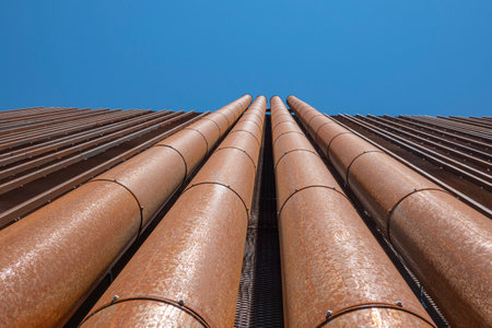 Modern urban background. Rusty papes on the building wall. Low angle view