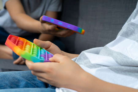 Teenage boys hands playing with rainbow push pop fidget toys at home. Close upの写真素材