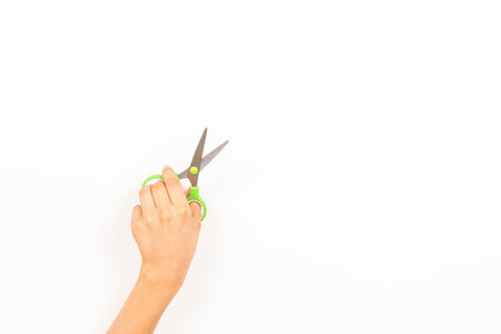 Kid left hand holding scissors over white background. Top view, copy space for text. Left Handers Dayの写真素材