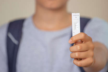 Teenage boy hand shows rapid Coronavirus Covid-19 negative test device with negative test result