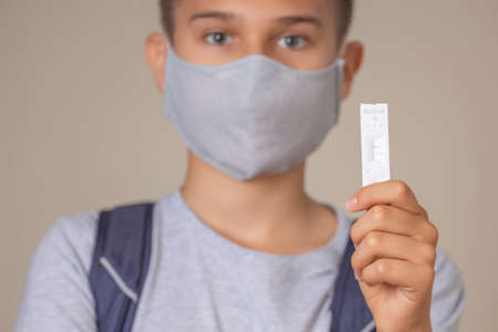 Teenage boy with face protective mask shows rapid Coronavirus Covid-19 negative test device with negative test resultの写真素材