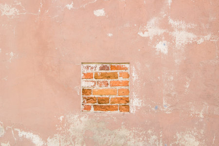 Old red brick and painted plaster wall with cracked shabby surface texture background.の写真素材