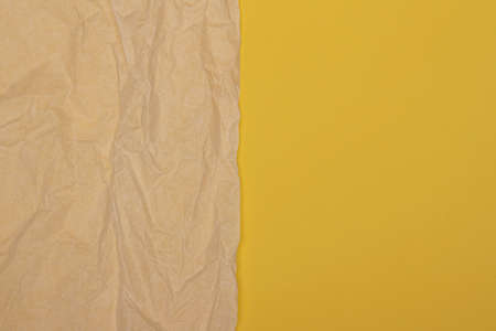 Beige old wrinkled creased paper sheet on yellow color background. Top view, copy space for textの写真素材