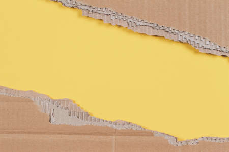 Old brown corrugated cardboard pieces with ragged edge on pastel yellow backgroundの写真素材