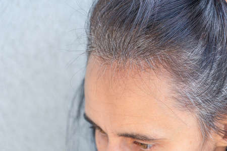Close up of middle age caucasian woman with dark brown hair and regrown gray hair rootsの写真素材