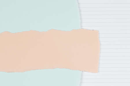 Torn paper textured collage background. Grunge ripped pastel paper piece with ragged edge on light blue and lined paper backgroundの写真素材