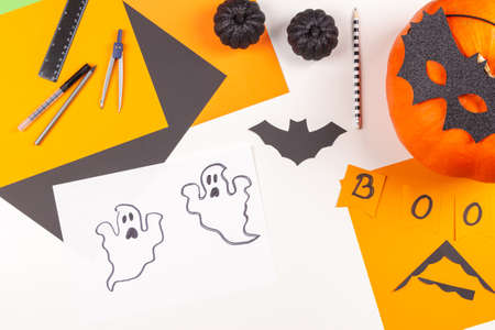 Halloween background. White table with Halloween party decorations, colored paper, drawings, scissors, pencils, pumpkin. Top viewの写真素材