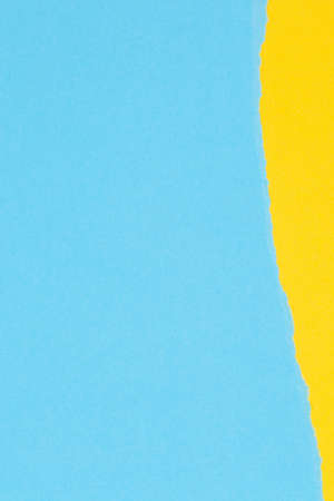 Torn grunge ripped yellow paper on light blue color paper banner backgroundの写真素材