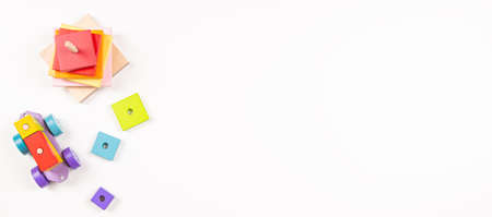 Baby kids toys background. Top view to wooden toy train, wood stacking pyramid tower and colorful wood bricks on white background. Early education, zero waste, Montessori toys for childrenの写真素材