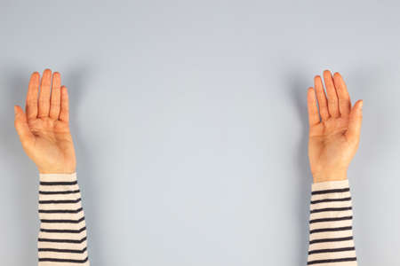 Two open empty woman palm hands over light gray background. Top view, copy space for text