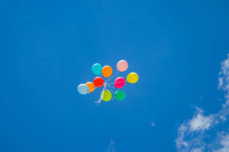 Bunch of flying colorful balloons on beautiful sky background. Low angle viewの写真素材