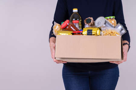 Woman volunteer hands holding food donations box with food grocery products