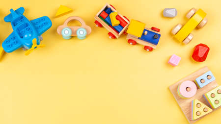 Baby kids toy for children. Educational wooden and plastic toys on yellow background. Top view, flat layの写真素材
