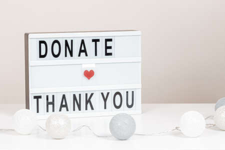 Christmas donation, charity. White lightbox with message Donate and Thank you standing on the table. Front view, close upの写真素材