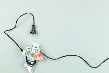 Euro banknotes are tightly wrapped with electric power cable cord. Energy efficiency, power...