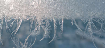 Winter banner background. Frozen window in winter time. Frost pattern on the window. Icy flowers on...