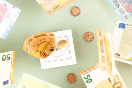 Euro money paper banknotes fall into a white electric socket on light green background. Increasing...