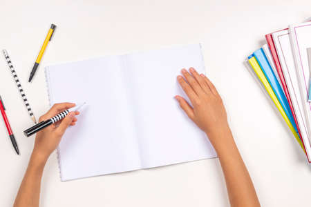 Kid hand holding pen in left hand and writing in open notebook, doing homework. Left Handers Dayの写真素材