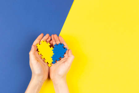 World Down syndrome day background. Hands holding blue and yellow Down syndrome awareness day heart...