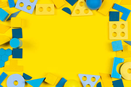 Baby kid toys background. Educational wooden Montessori toys on yellow background. Top view, copy...
