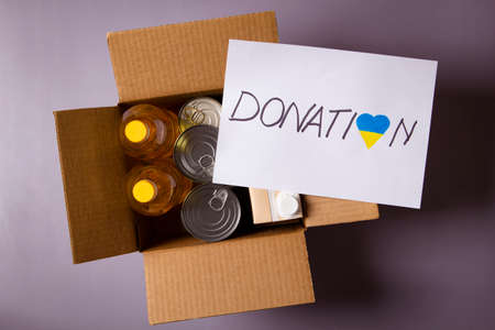 Donation for people from Ukraine. Food donations boxes with grocery products and white card with...
