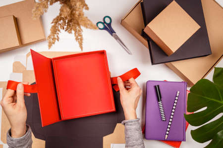 Top view to woman hands open empty present package box on the table. Startup small business freelance workspace, online marketing, handmade craft, self employed, small family business conceptの写真素材