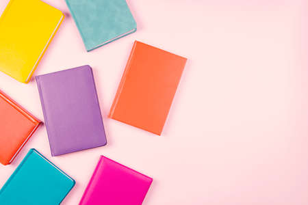 Colorful hardcover books on pastel pink background. Top view, copy space for textの写真素材