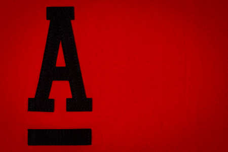 Letter A. Alphabet letter A application and blank label tag made from black material on red fabric backgroundの写真素材