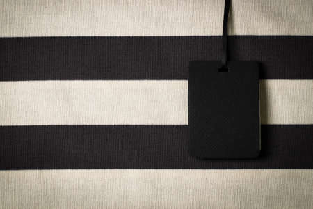 Blank black rectangular label tag on striped clothes background. Price tag tabel mock up with copy spaceの写真素材