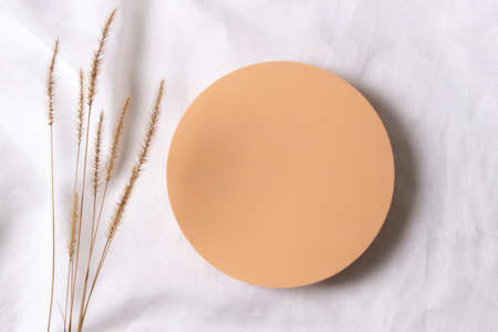 Blank pastel round platform podium for cosmetics or products and dry grass plant on white linen fabric background. Top viewの写真素材