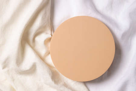 Blank pastel round platform podium for cosmetics or products on natural white linen fabric background. Top view, copy spaceの写真素材