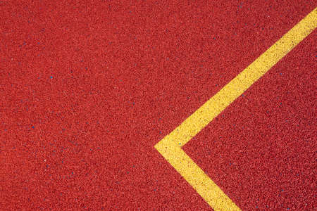 Colorful sports court background. Top view to red field rubber ground with yellow corner lines outdoorsの写真素材