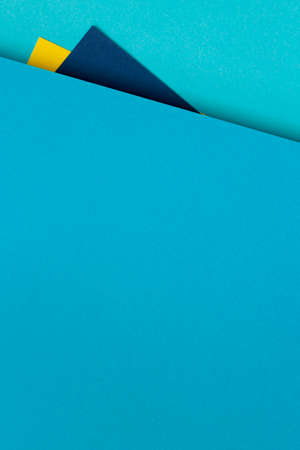 Abstract multicolored paper geometry flat lay vertical composition background with blue and yellow...